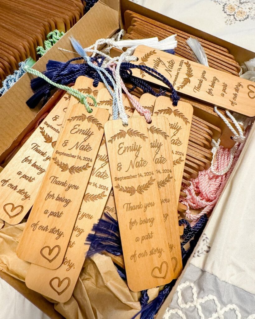Wooden engraved bookmarks with colorful tassels arranged in a cardboard shipping box