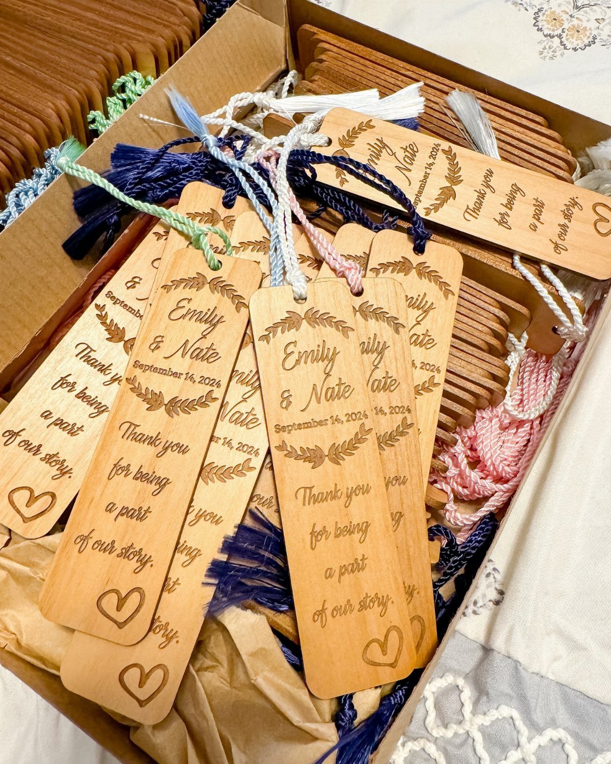 Wooden engraved bookmarks with colorful tassels arranged in a cardboard shipping box