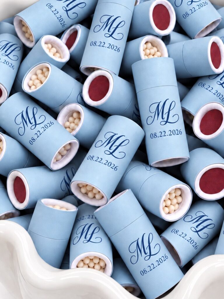 Light blue personalized wedding favor tubes with monograms and dates in a bowl