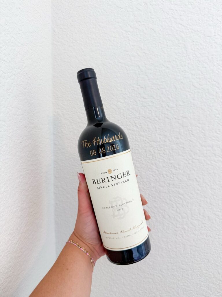 Wine bottle with gold personalized date and names on the dark glass neck.