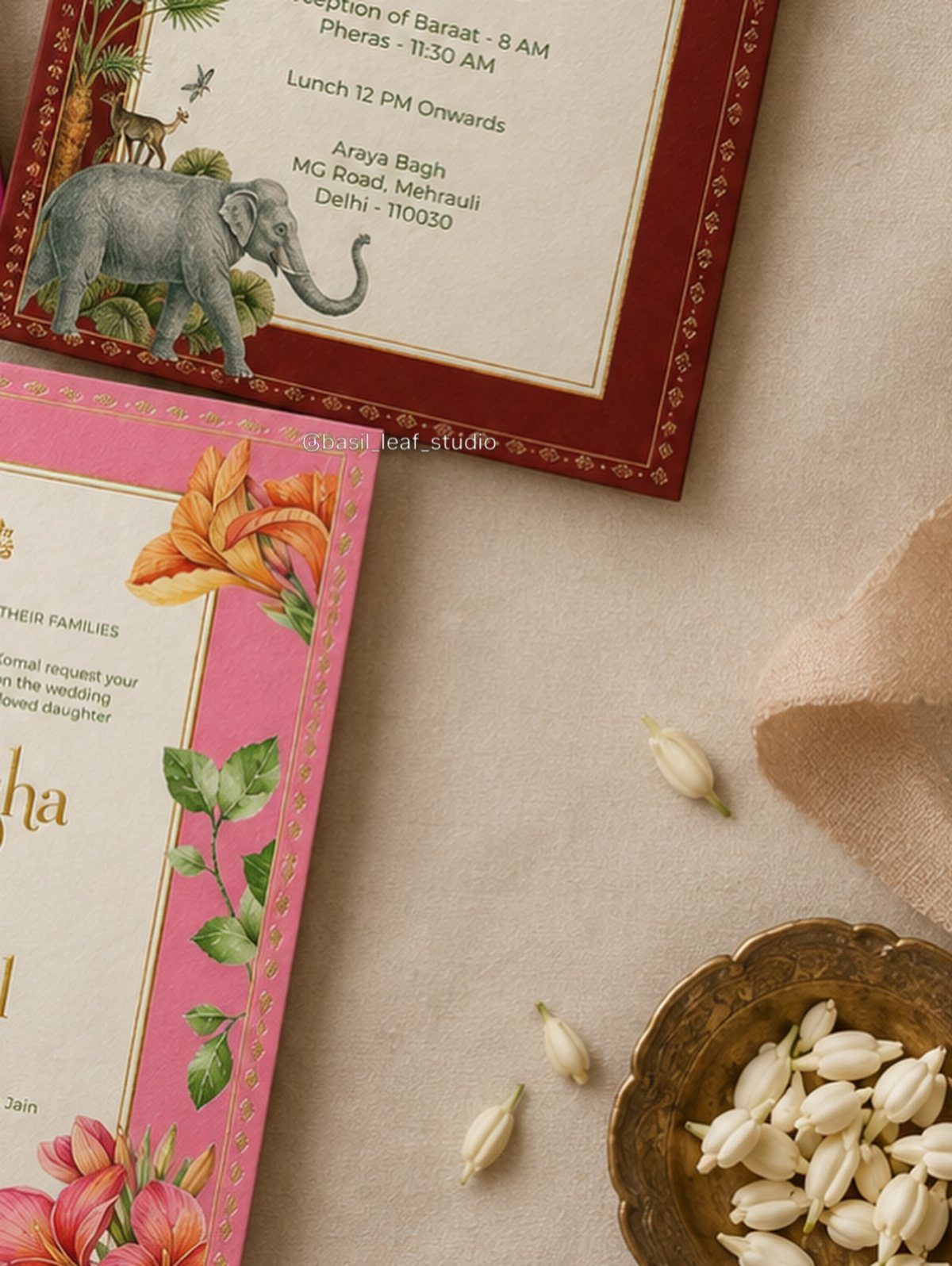 Colorful wedding invitation cards with floral and elephant designs and jasmine flower buds.