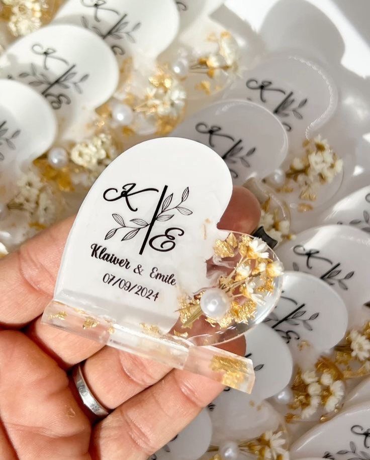 White arched resin wedding favors with gold flakes, dried flowers, and personalized text.