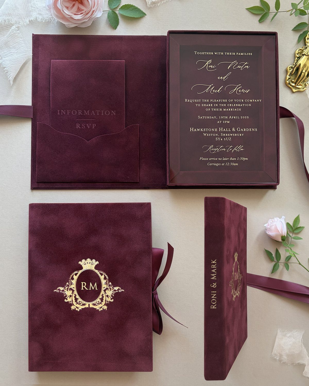Burgundy velvet invitation boxes with gold lettering and floral accents on a table