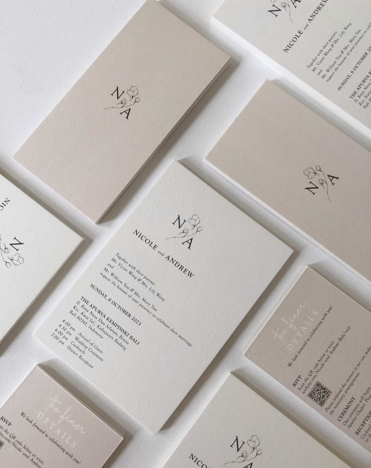 Minimalist wedding invitation cards with black text and floral monograms on off-white paper.