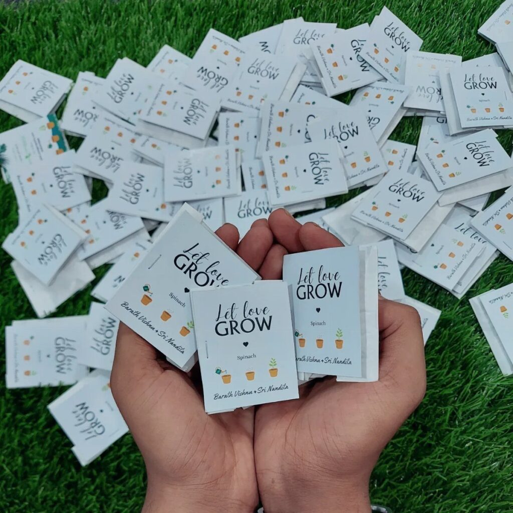 Hands holding white seed packets with Let love GROW text on green grass