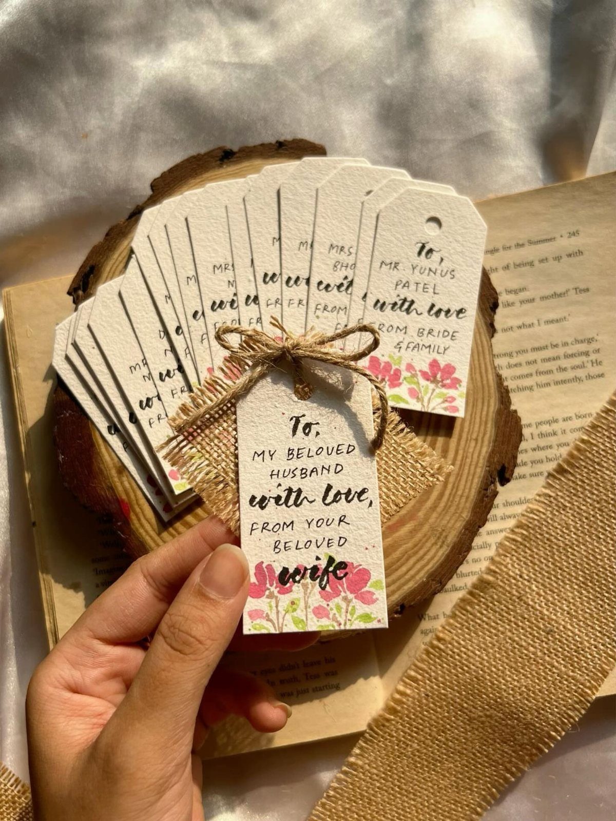 Hand holding a floral wedding gift tag with a romantic message on wood.