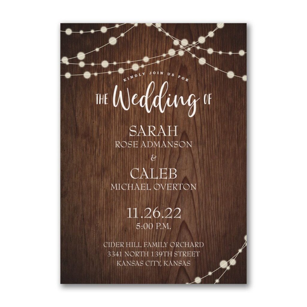 Wedding invitation with dark wood texture background and glowing string light accents.