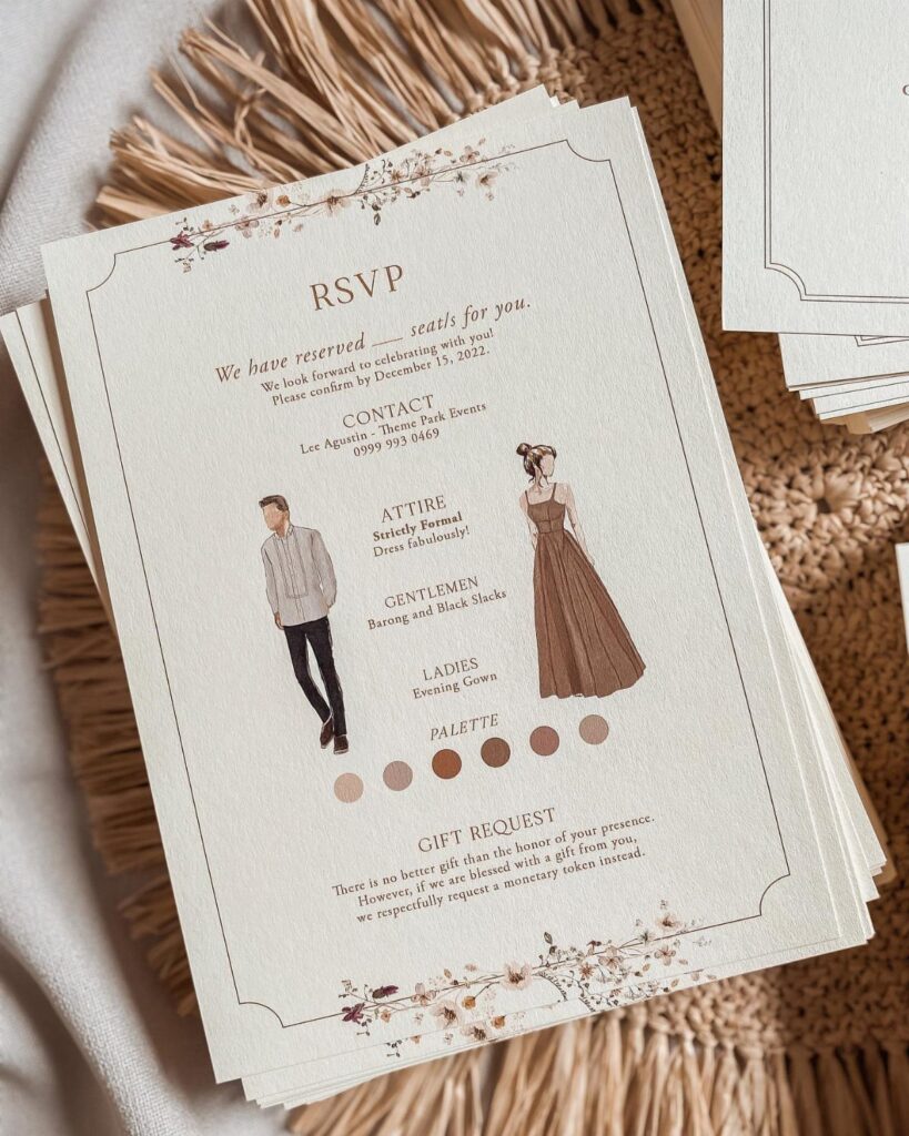 Cream RSVP cards with floral accents and attire illustrations on a woven mat.