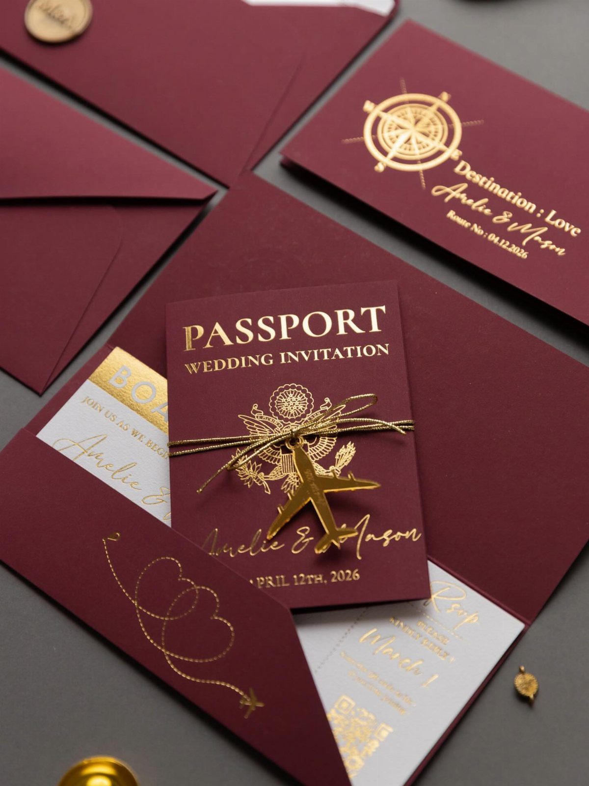 Passport style wedding invitation in burgundy and gold with a small airplane charm.