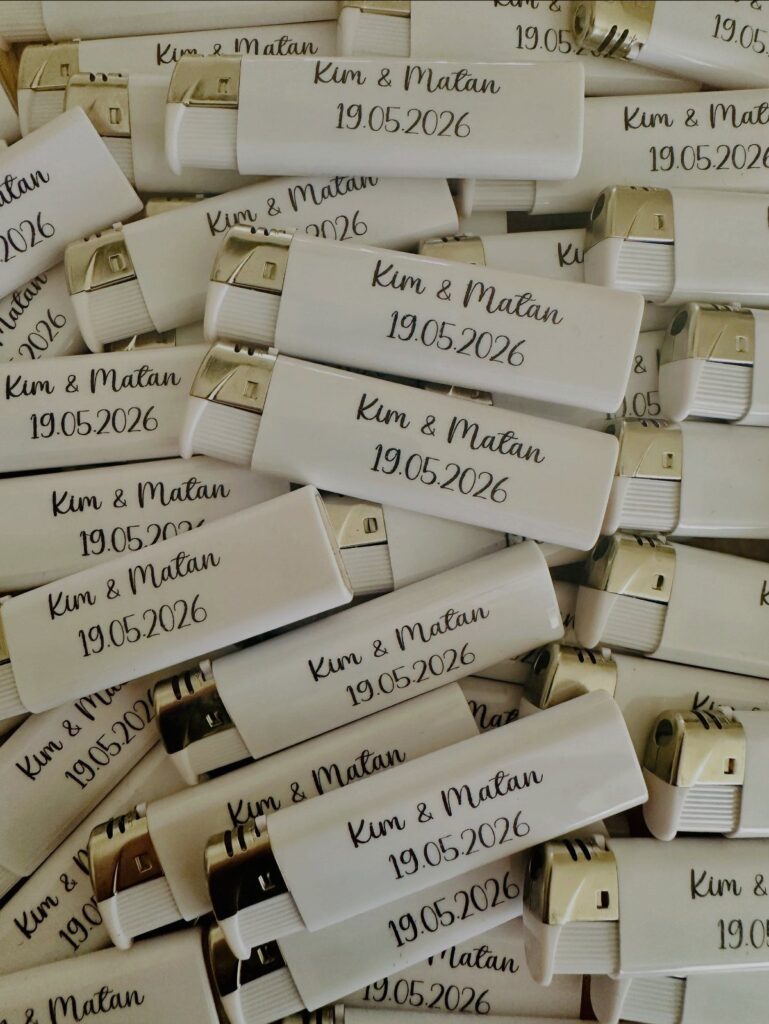 White personalized wedding lighters with gold tops and black cursive text.