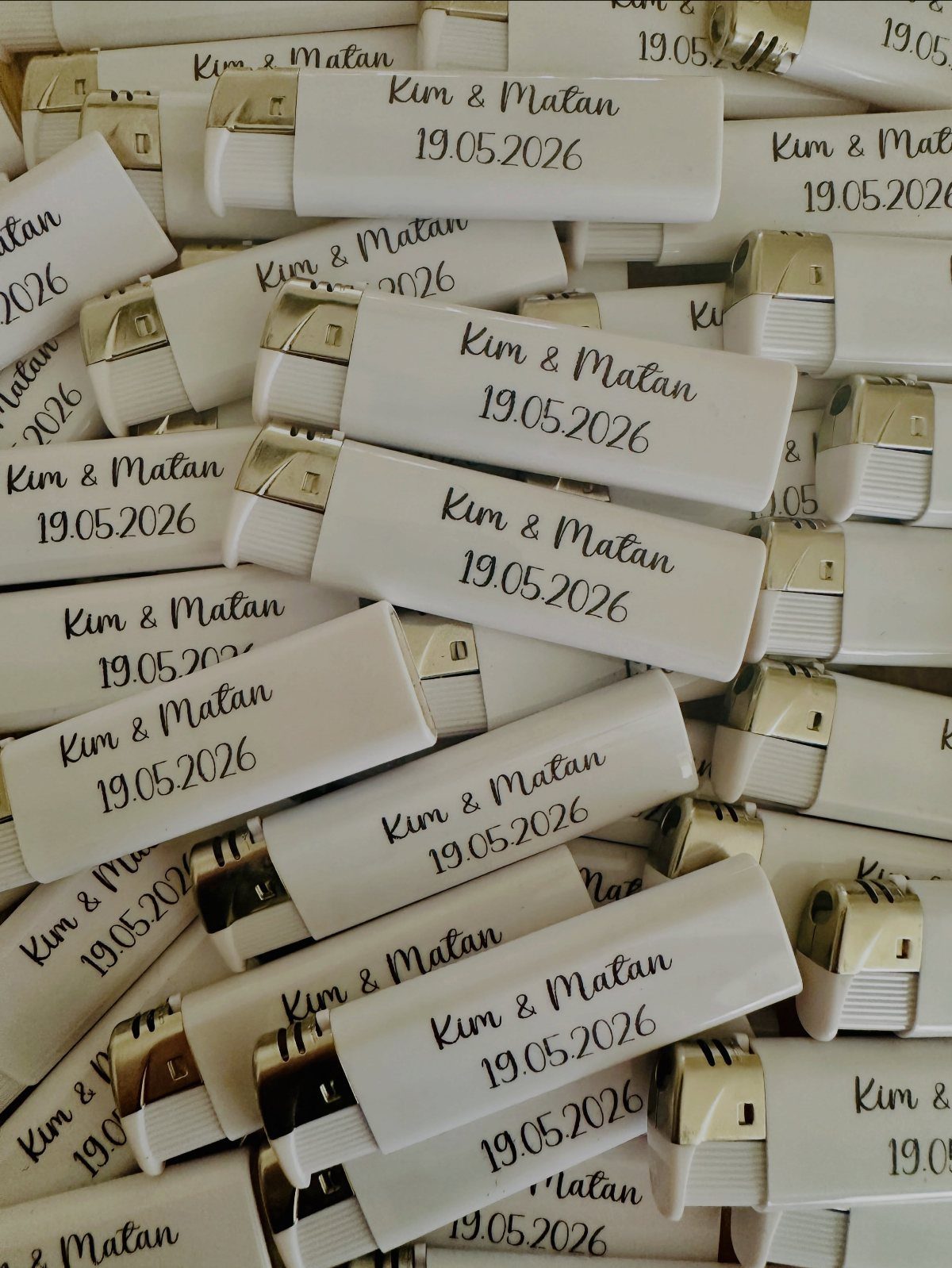 White personalized wedding lighters with gold tops and black cursive text.
