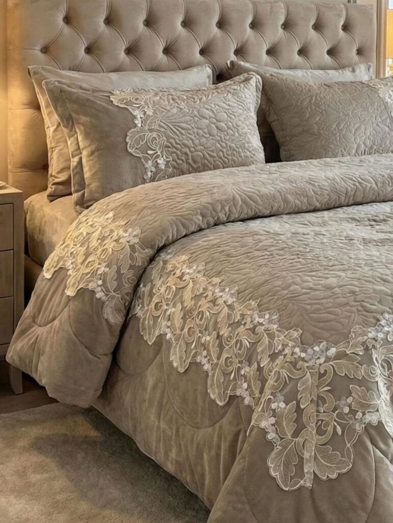 Luxury champagne bedding set with white lace embroidery on a tufted bed.