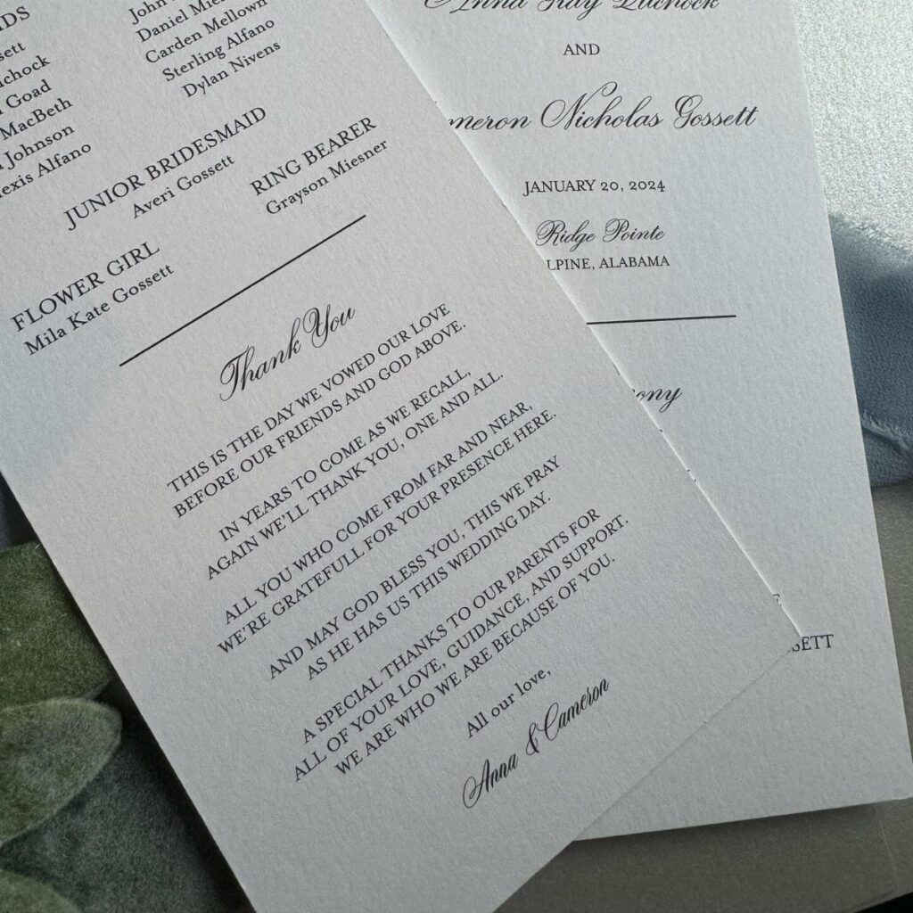 White textured wedding program cards with elegant black text and a grey leaf.