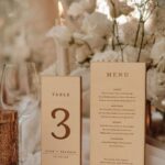 Wooden table number and menu signs on a wedding table with white flowers.