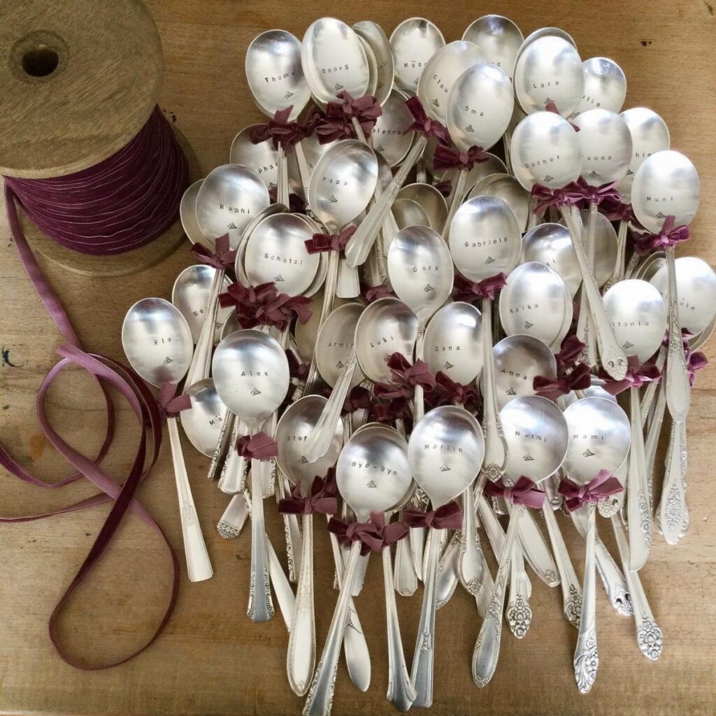 Silver spoons tied with burgundy ribbons as wedding favors on a wooden table